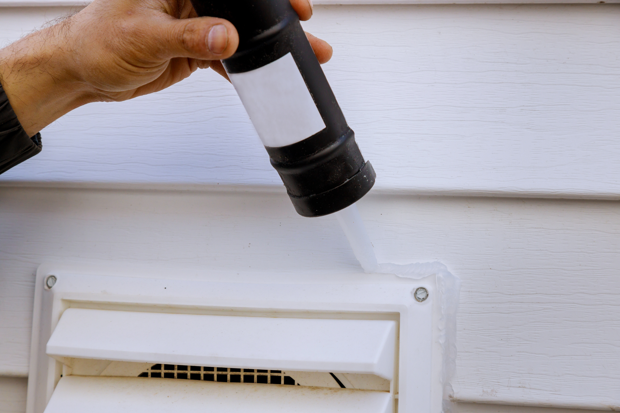 person caulking exterior vent on San Antonio home